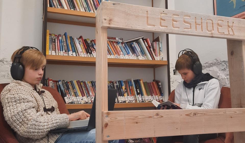 Kinderen met koptelefoon en boeken in de leeshoek in de klas