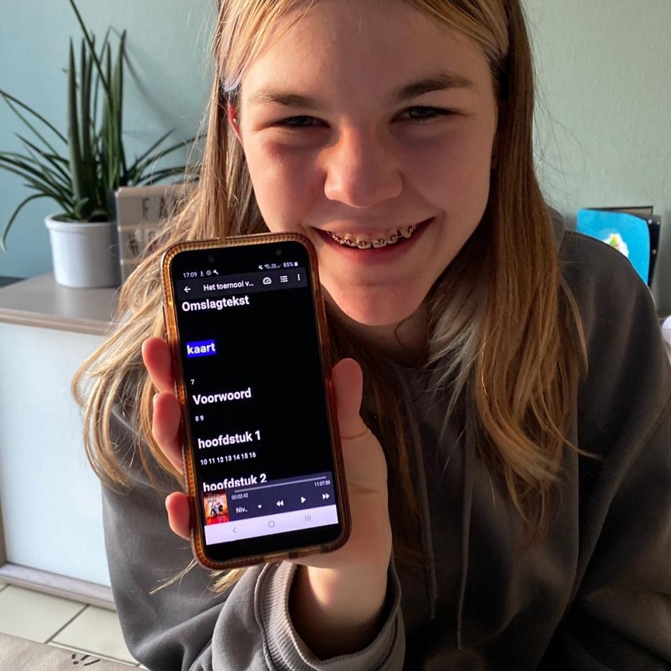 Een meisje toont vol enthousiasme de Anderslezen-app op haar smartphone